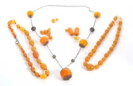 A quantity of faux amber jewellery to include two graduated oval bead necklaces, a white metal and