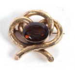 A smokey quartz brooch, the oval mixed cut smokey quartz, collet mounted within three loops of