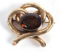 A smokey quartz brooch, the oval mixed cut smokey quartz, collet mounted within three loops of