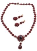 A late 19th century garnet necklace and matched earrings, the necklace set with a central round