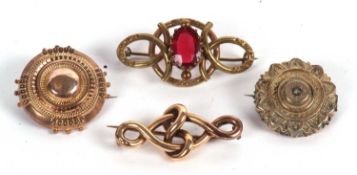 Four unmarked yellow metal brooches: to include a red paste set brooch, a yellow metal knotted bar