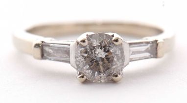 A 14k white gold diamond ring, the central round brilliant cut diamond set to either side with a