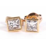 A pair of diamond earstuds, set with collet mounted princess cut diamonds, total estimated approx.