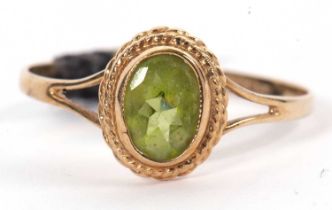 A 9ct oval peridot ring, the oval mixed cut peridot in a collet mount with rope twist border,