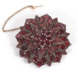 A garnet brooch, the round cluster brooch comprised of three tiers of mixed cut garnets in a star