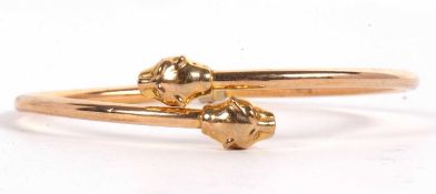 A 9ct lion head bangle, the spring hinged open ended bangle with a naturalistic lion head to
