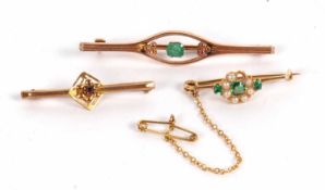 Three bar brooches: the first a 9ct emerald bar brooch, 5cm long, 1.9g, cased; an unmarked emerald