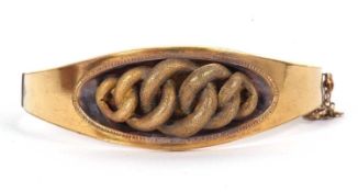 A late Victorian unmarked hinged bangle in fitted case, the central section with raised textured