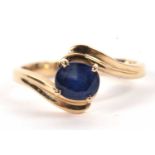 A 14ct sapphire ring, the oval sapphire in a four claw mount to a crossover style band with reeded