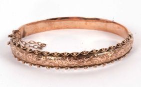 A 9ct hinged bangle, with engraved decoration to upper half with bead and rope twist border, plain