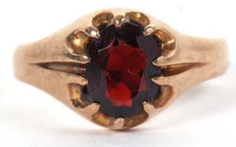 A 9ct garnet ring, the central oval garnet, claw mounted to reeded shoulders and tapered band,