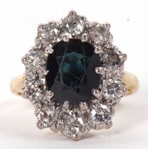 An 18ct sapphire and diamond ring, the central oval deep blue/green sapphire surrounded by round