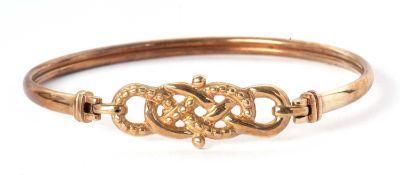 A yellow metal bangle, the centre with a knotted design with beaded texture, with hook clasp to