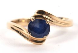 A 14ct sapphire ring, the oval sapphire in a four claw mount to a crossover style band with reeded