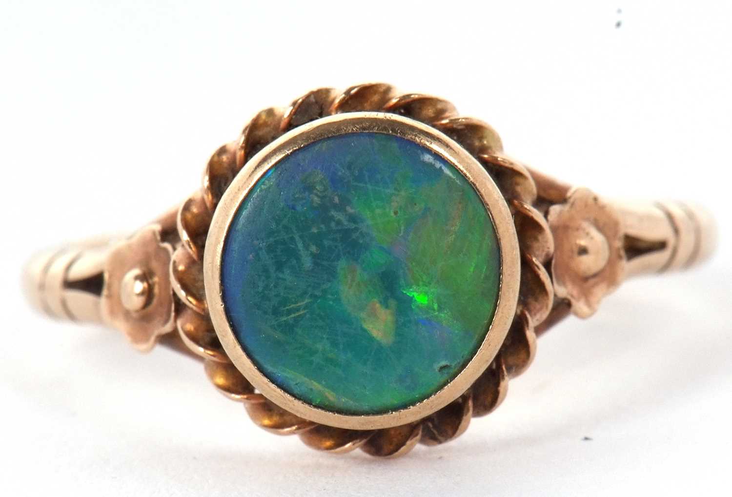 A 9ct opal ring,the round opal cabochon, collet mounted with rope twist border and closed back, 10.