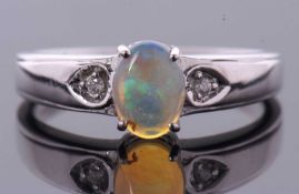 A 9ct white gold opal and diamond ring, the oval opal cabochon, approx. 8mm long, in a four claw