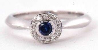 A sapphire and diamond cluster ting, the central round collet mounted sapphire, surrounded by