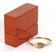 A 9ct Clogau gold bangle, with two tone gold panel with grid design, hinged to both ends with one