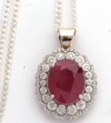 An 18ct ruby and diamond cluster pendant, the oval ruby, approx. 14 x 10.8 x7.6mm, in a four claw