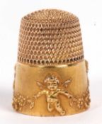 An unmarked yellow metal thimble, with embossed cherubs and swags around the outer edge, size 6, (