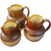 A graduated set of three Doulton stone ware Harvest type jugs