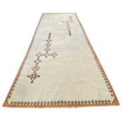Large 20th Century pale wool rug with rust coloured border and tasselled ends, 250cm x 550cm