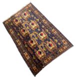 An unusual Middle Eastern wool floor rug decorated with a central panel of stylised buildings and