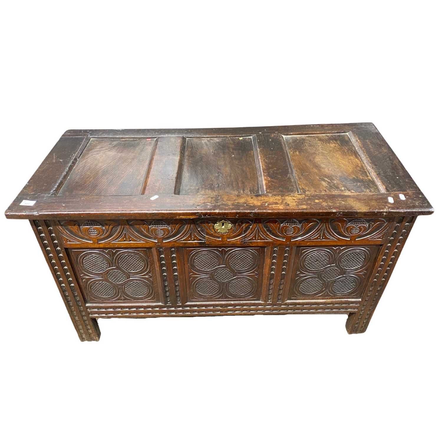 18th Century oak coffer with panelled lid over a carved three panelled front raised on style feet,