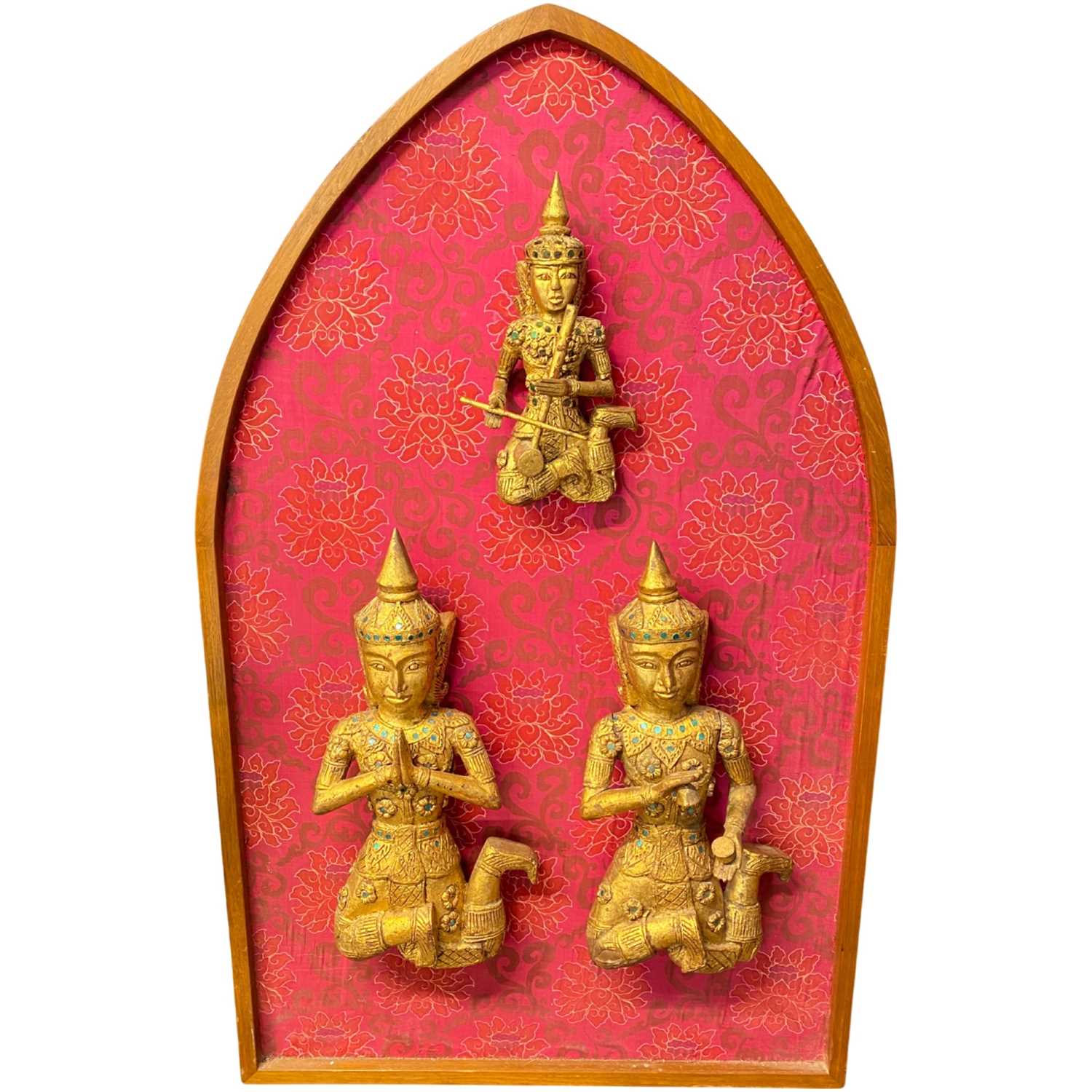 A group of three 20th Century carved and gilded Thai temple figures mounted on a hardwood and silk