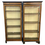 A pair of Victorian ebonised and inlaid narrow display cabinets with glazed doors, fitted shelves