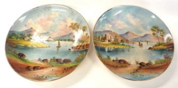 A pair of continental pottery dishes both painted with landscape and river scenes, 29cm diameter