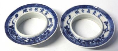Two Chinese porcelain cup holders with caligraphy around the rim