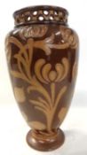 A Doulton Lambeth vase decorated with tube lined brown foliage on a brown ground with pierced neck