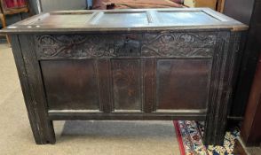 An 18th Century oak coffer with hinged panel lid over a base with three panelled front and