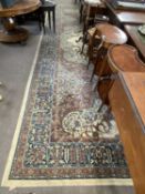 A large mid 20th Century machine made floor rug decorated with a large central floral panel on a