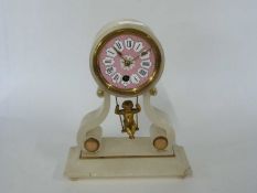 A French style alabaster clock with a pink dial and a gilt brass model below of a boy on a swing