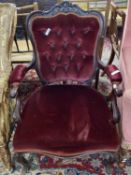 A Victorian red upholstered button back armchair with carved showwood frame raised on short cabriole