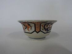 Japanese porcelain bowl of flared form decorated in Imari style with panels of dragons chasing the