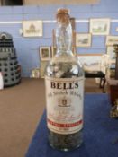 Eight pint glass bottle of Bells Old Scotch Whisky filled to the neck with sixpences, mainly modern,