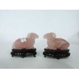 Pair of pink jade rams on wooden bases, 9cm long