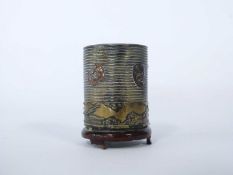 Small Chinese metal cylindrical pot with ribbed design and Chinese faces on a wooden base, 5cm high