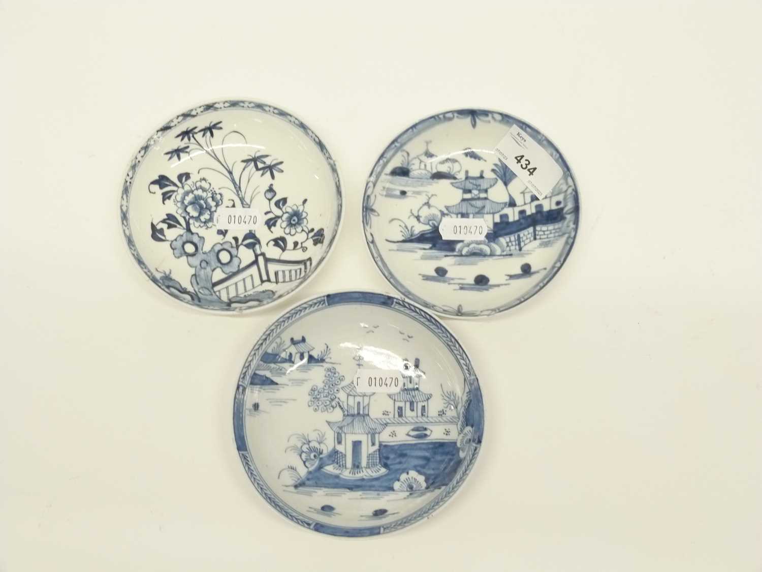 Three Lowestoft blue and white saucers, two with pagoda river scenes, one with a floral and fence