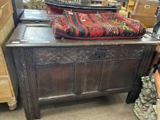 An 18th Century oak coffer with hinged panel lid over a base with three panelled front and