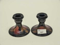 Two Moorcroft candlesticks decorated in the pomegranate pattern on dark blue ground, 8cm high