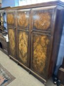 An early 20th Century walnut triple door wardrobe with shaped cornice and inlaid decoration, 190cm