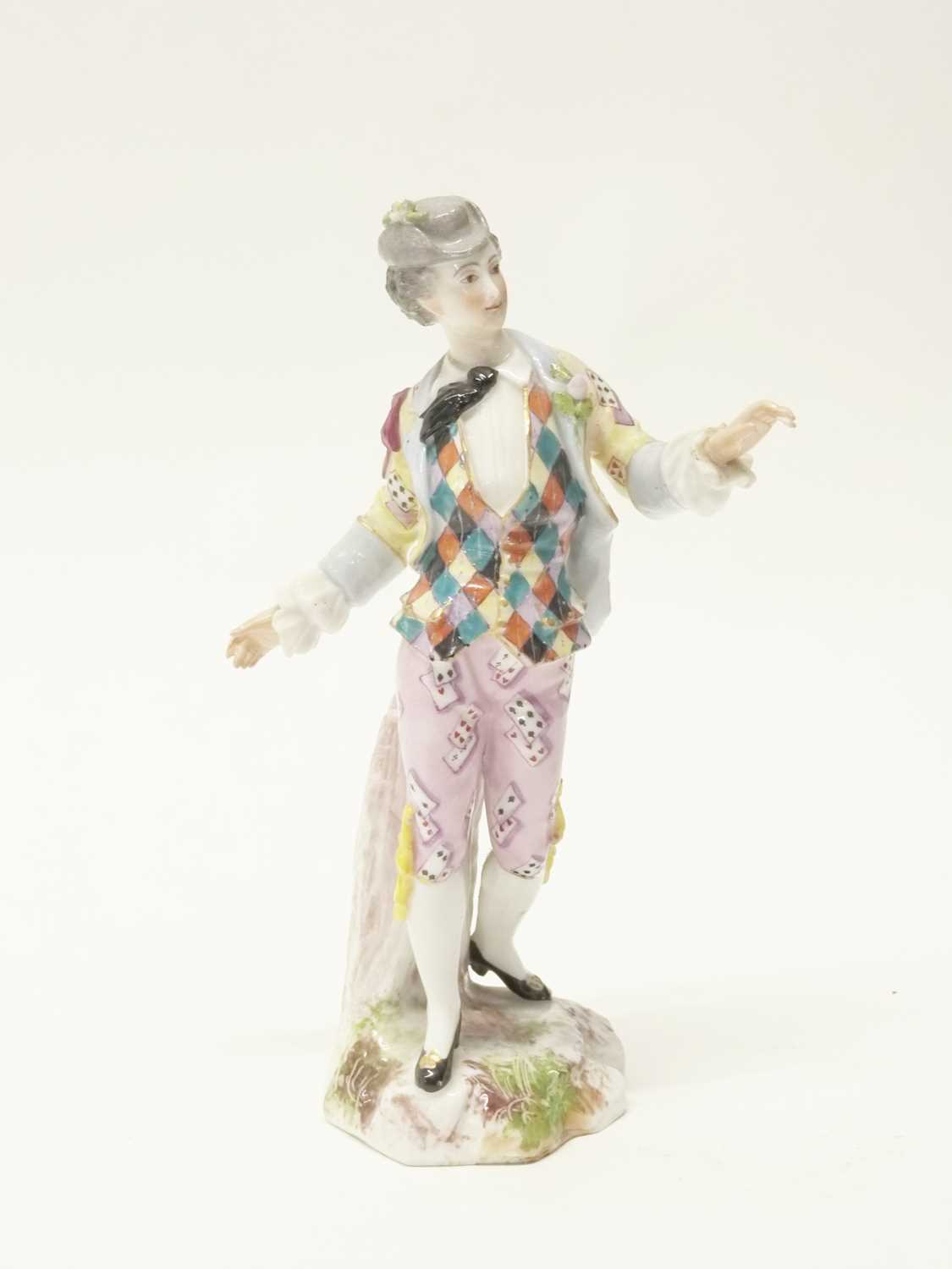 A continental porcelain figure of a gentleman depicting harlequin, cross swords and E mark in blue