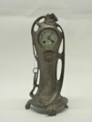 An Art Nouveau mantle clock, with bronzed case with verdigris style finish, cream enamel dial with