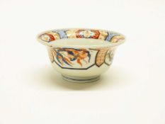 Japanese porcelain bowl of flared form decorated in Imari style with panels of dragons chasing the