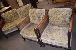 An early 20th Century Bergere three piece suite with floral upholstered loose cushions, largest