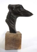 A metal figure of a greyhound head mounted on a wooden rectangular block, 13cm high